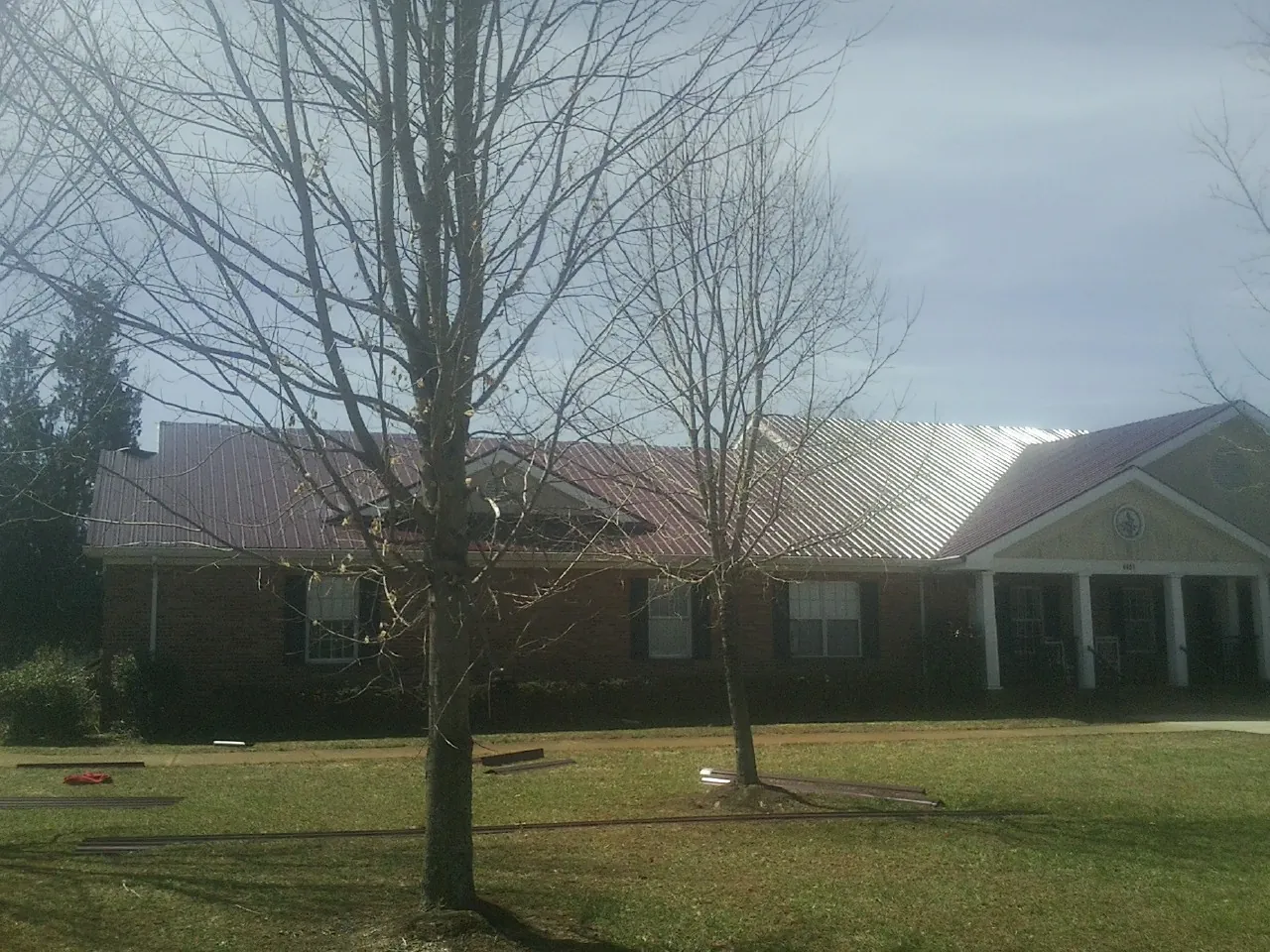 Red metal roof on a brick building seen from the front lawn in Kandiyohi