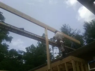 Carpenter setting a ridge beam over a new addition frame — Ice Dam Removal by Roofing Brothers in Kandiyohi