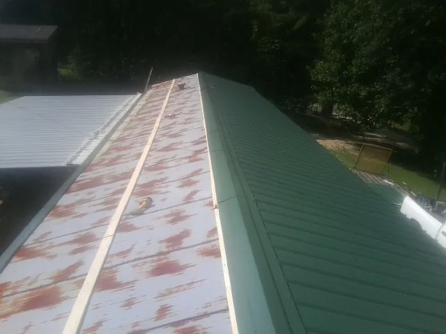 Old rusted panels beside newly installed green metal roofing — Wind Damage Roof Repair by Roofing Brothers in Kandiyohi