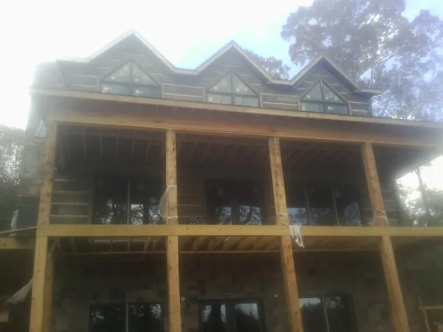 Dormers and porch framing on a large log home under construction — Roof Coating work by our crew in Kandiyohi