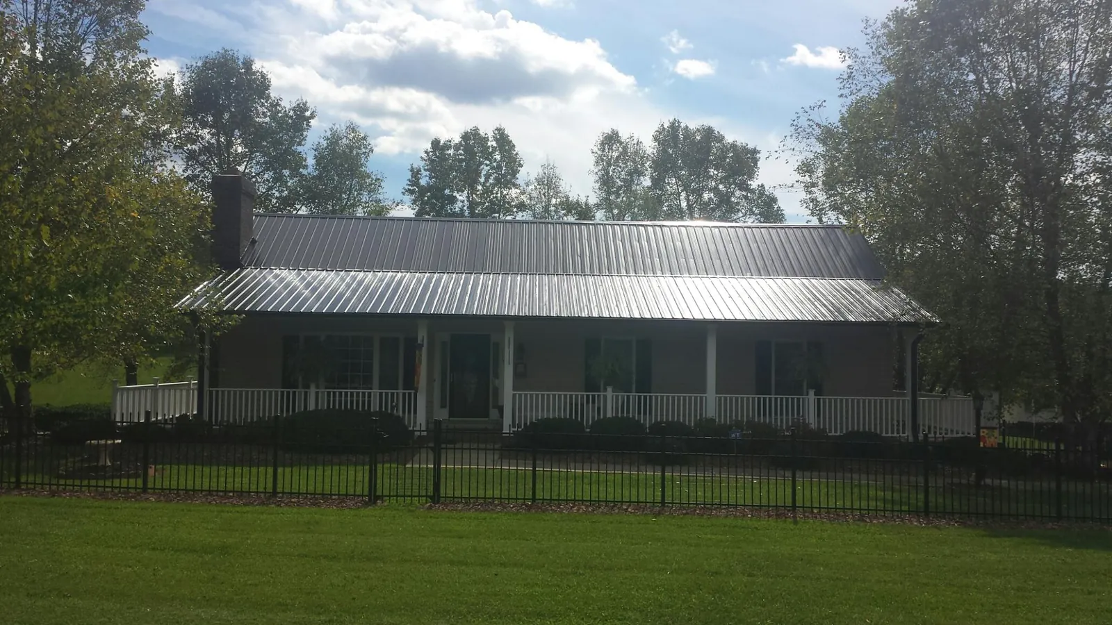 Gray metal roof on a brick ranch with a full width front porch — Gutter Guard Installation work by our crew in Kandiyohi