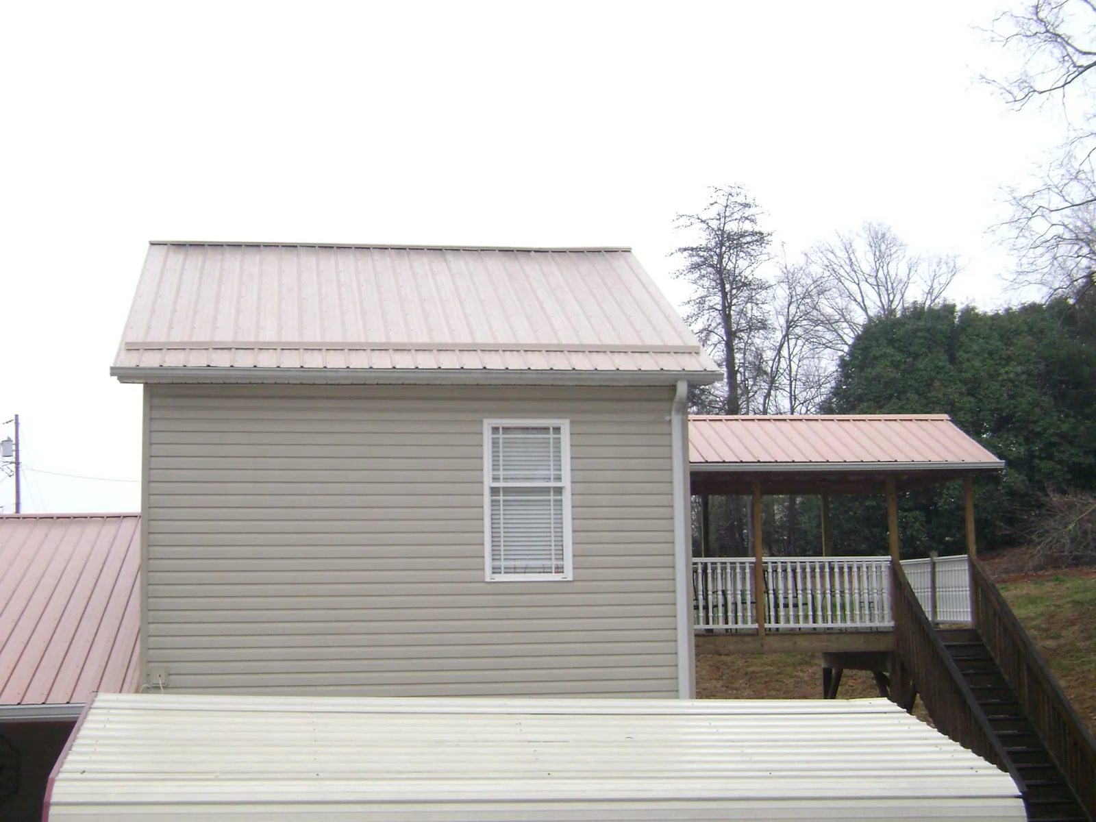 Tan metal roofs on a two story addition and attached porch, from a Roof Replacement job in Kandiyohi