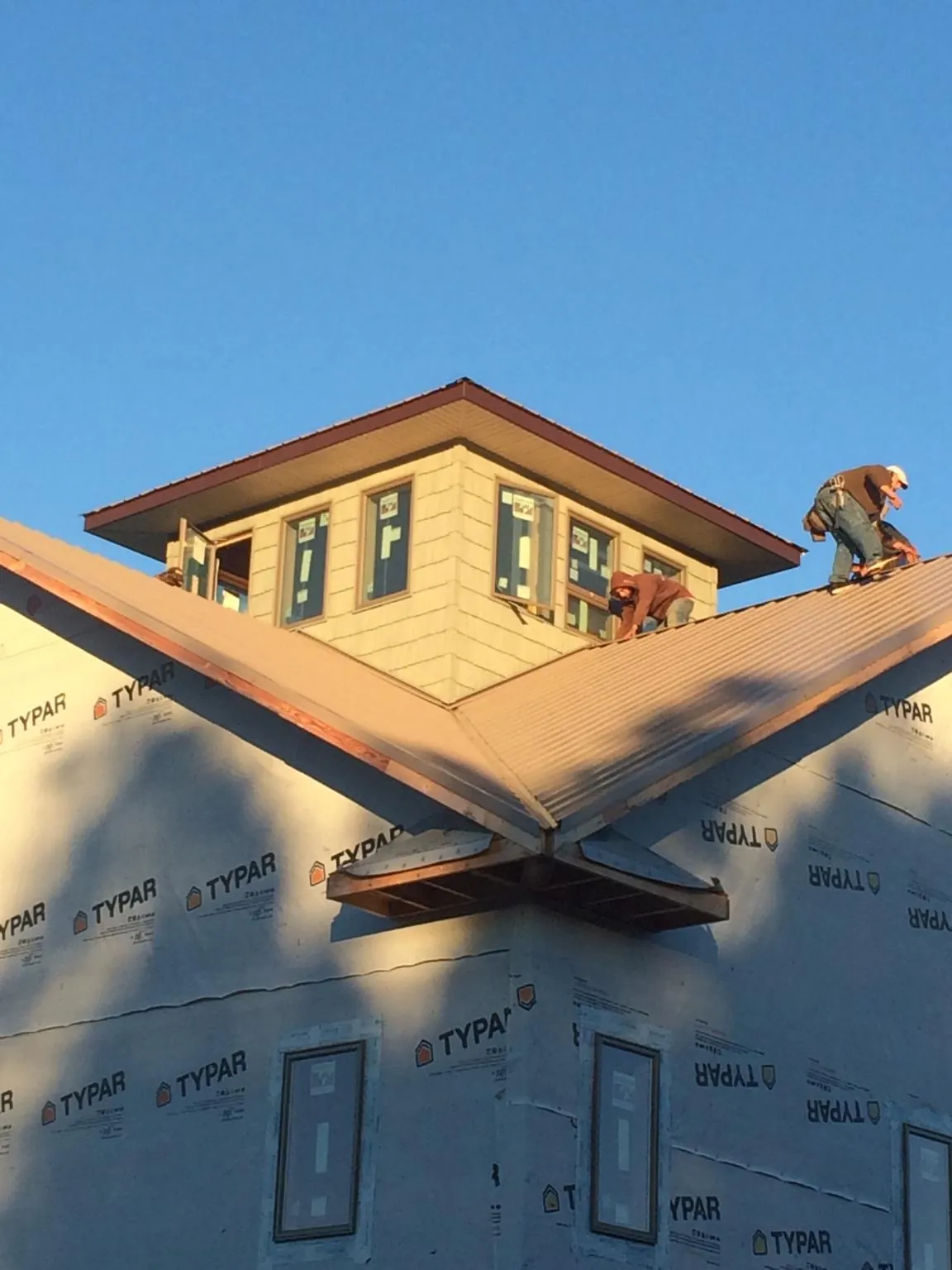 Roofers working around a rooftop cupola on a new metal roof at sunset — Roof Waterproofing in Kandiyohi by Roofing Brothers